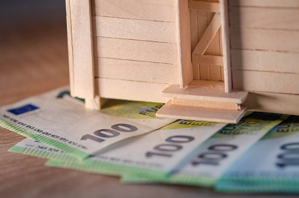 一座木制房屋模型，代表小屋，上面堆满了100欧元钞票 - 股票照片图片下载