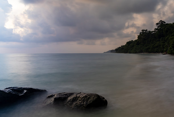 黎明时分，从岩石海岸拍摄的海平面上方的多云天空长时间曝光照片图片下载