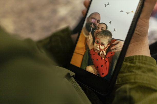 一个幼儿在手机上浏览她的家庭照片。情人节，家庭团聚。妈妈、爸爸和即将出生的宝宝。特写照片。图片下载