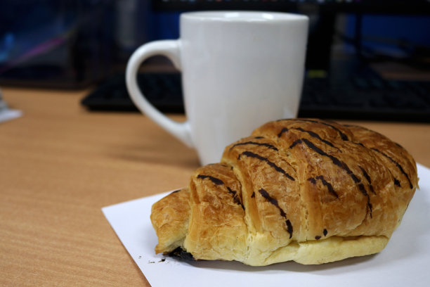 办公室桌上放着面包和一杯咖啡的照片图片下载