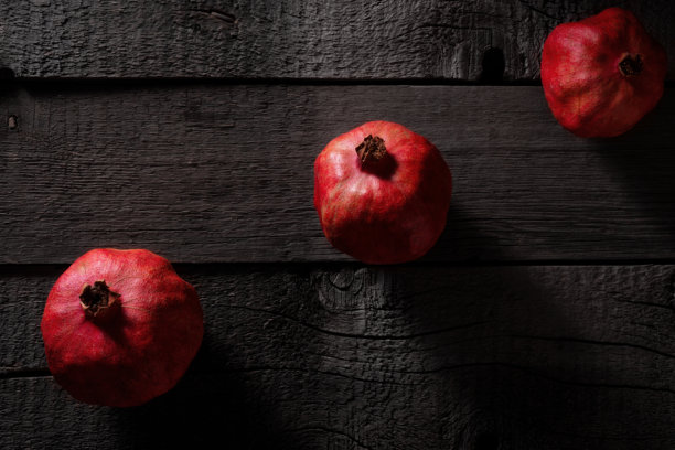 木质旧桌面上的石榴果实。选择性照明艺术照片。图片下载