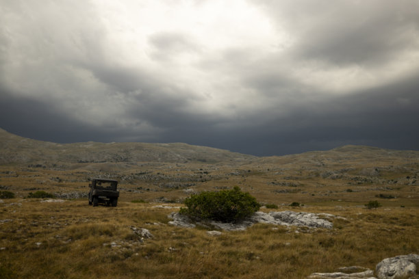 越野车在崎岖的山地地形下穿行，背景是戏剧性的天空图片下载