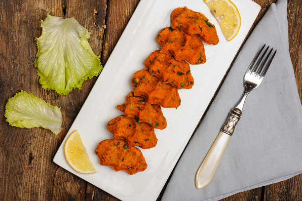 红扁豆饼的俯视照片，这是一种受欢迎的传统土耳其食品，也被称为mercimek köftesi，摆放在复古木桌上，旁边有生菜叶、亚麻餐巾和一把优雅的叉子。图片下载