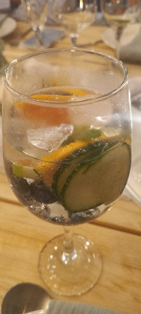 特写照片：一杯装满新鲜金汤力的玻璃杯，里面有黄瓜片、葡萄柚、蓝莓，并加满冰块。图片下载