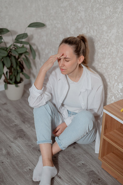 年轻女性在现代客厅的沙发上坐着，白天感到头痛，竖版照片图片下载