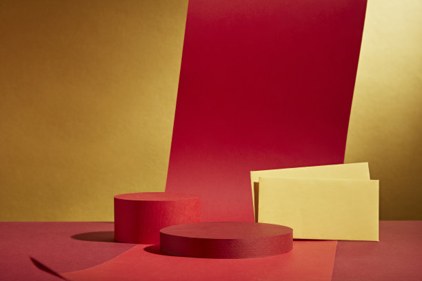 两个圆形展示平台，正面角度展示，装饰有红色纸绳和黄色红包。非常适合在金色背景下拍摄的春节照片。图片下载