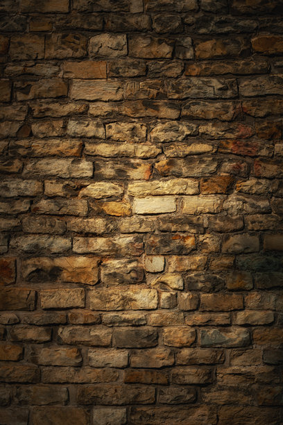 古老的风化砖墙的深米色背景，来自古董城堡，中央有淡渐变光斑。适合用作垂直的情绪背景或装饰的艺术照片。图片下载