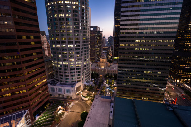 黄昏时分，洛杉矶中央图书馆在市中心摩天大楼后方的航拍镜头图片下载