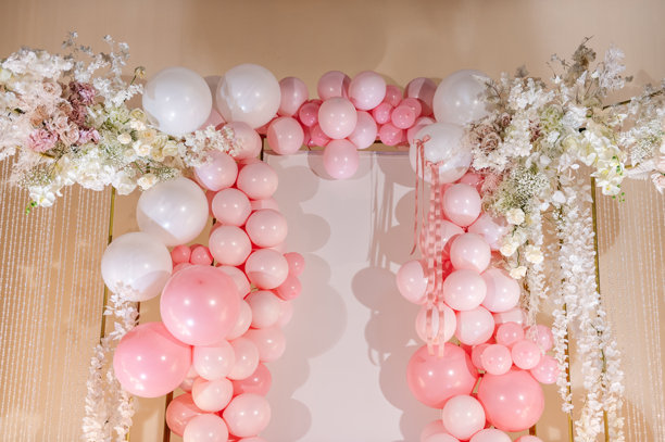 婚礼接待的拍照区，或庆祝女孩生日派对的节日区域。用粉色和白色气球、花朵装饰的拱门。照片墙装饰空间或文字展示区。图片下载