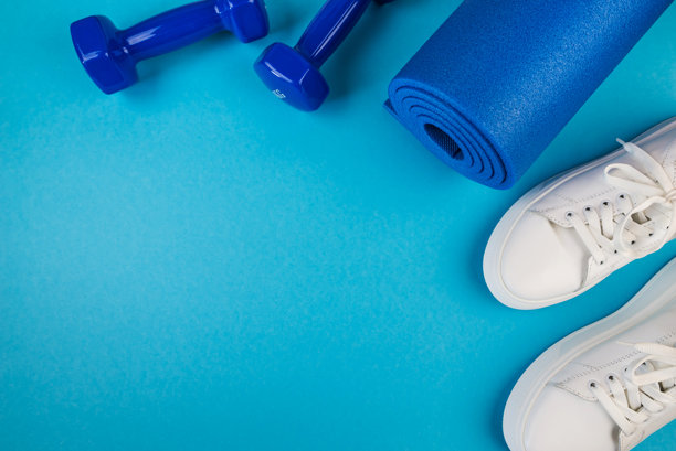 运动配件的概念。蓝色哑铃和蓝色瑜伽垫、白色运动鞋及其他运动器材的照片。运动、健身、瑜伽、减肥、健康生活方式的概念。图片下载