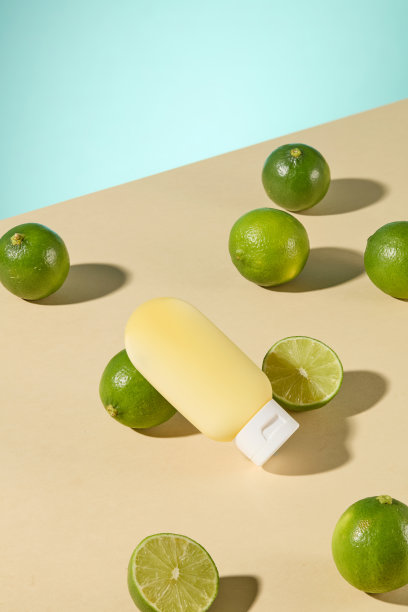 一张化妆品广告图片，正面视角的淡黄色挤压瓶模型，躺在米色表面上，旁边放着几颗青柠。背景是浅青色。图片下载