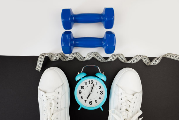 白色闹钟、哑铃、运动鞋及其他运动器材的俯视照片。瑜伽健身、运动减肥概念。图片下载