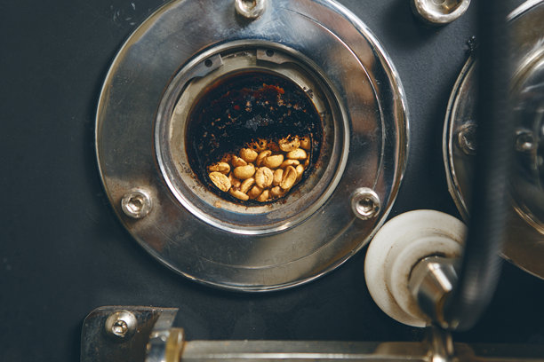 专业咖啡烘焙师的特写照片，带有小圆窗，透视可见的烘焙咖啡豆，以便分析烘焙程度。专业咖啡烘焙设备。图片下载