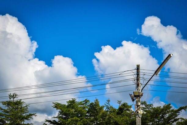 这张照片展示了高耸的电线杆和横跨天空的电缆。图片下载