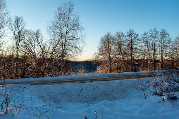 雪林中夕阳下的一条狭窄道路。适合出版、海报、日历、帖子、屏保、壁纸、封面和网站的冬季背景。高质量照片。图片下载