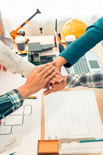 承包商和商人在建筑办公室握手，桌上放着房屋设计图，概念：合作与信任是成功项目的关键。特写照片图片下载