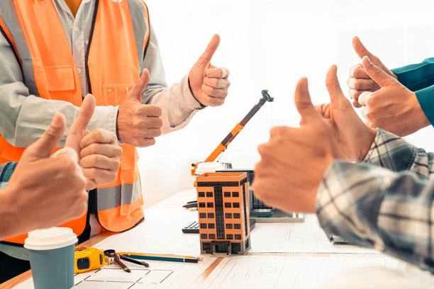 承包商和商人在建筑办公室握手，桌上放着房屋设计图，概念：合作与信任是成功项目的关键。特写照片图片下载