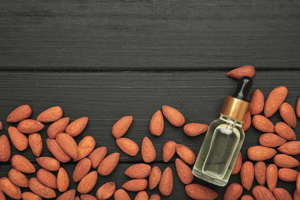 新鲜的杏仁油与杏仁坚果在黑色木质背景上。垂直照片图片下载