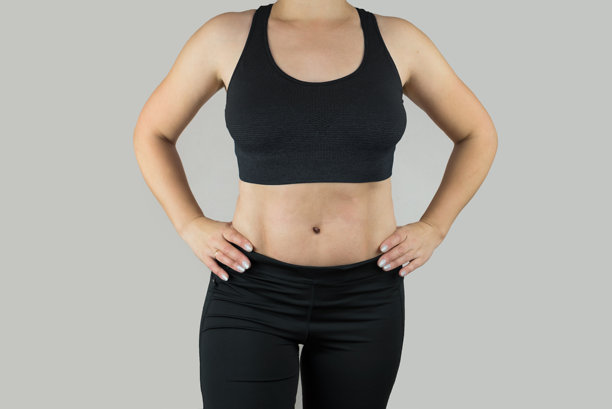 运动与瑜伽生活方式概念。年轻漂亮的强壮女性穿着运动服，时尚的上衣和紧身裤在灰色背景上摆姿势。裁剪照片。图片下载