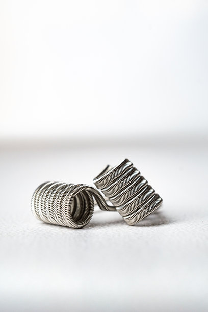 宏观特写照片，展示白色背景上的电子烟雾化器线圈，外星核心线圈，扭曲的杂乱线圈，铝制不锈钢材质。图片下载