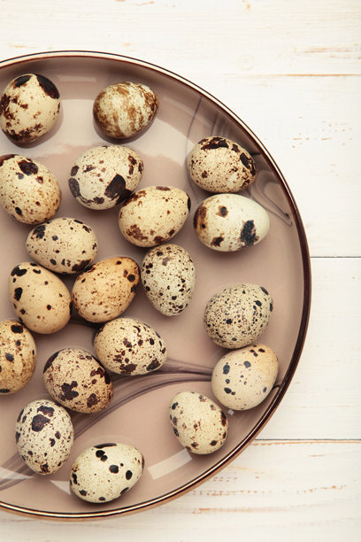 白色木质背景上的盘子里放着鹌鹑蛋。竖版照片图片下载