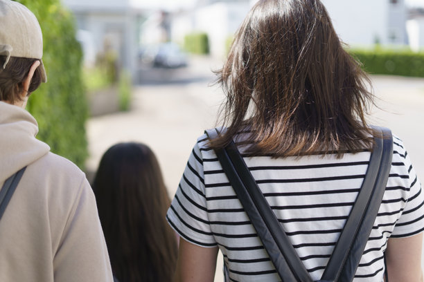 一张照片，展示了一家由不同年龄女性组成的家庭，从背后走在欧洲城市的街道上。图片下载