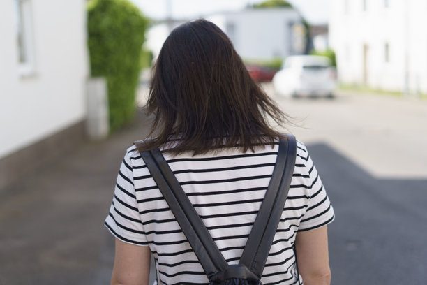 夏季户外人行道上，一个背着背包的女孩背影走路的照片。健康积极旅行的概念。图片下载