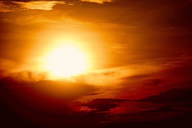 这是一张美丽的日落或日出照片，天空的主要颜色是明亮的橙色、黄色和红色。太阳部分被云层遮挡，使得天空看起来更加明亮和温暖。图片下载