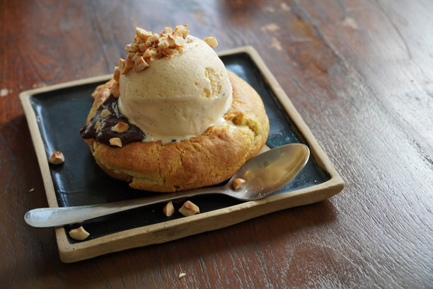 特写照片显示一勺香草味冰淇淋上面撒着花生碎，正在融化在饼干甜点上。图片下载