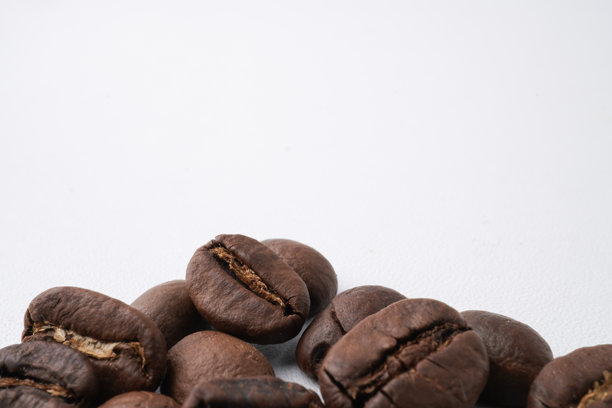烤制咖啡豆的特写照片，准备研磨。背景为白色。图片下载