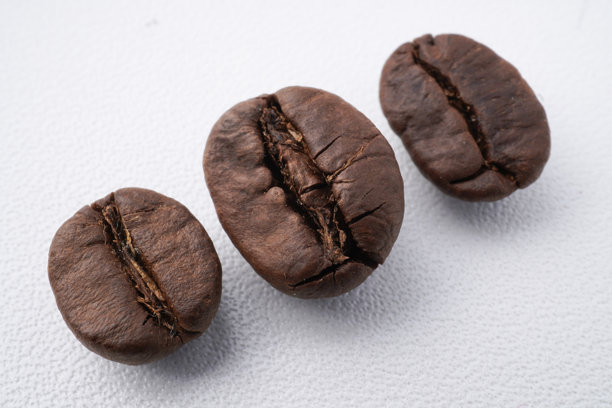 烤制咖啡豆的特写照片，准备研磨。背景为白色。图片下载