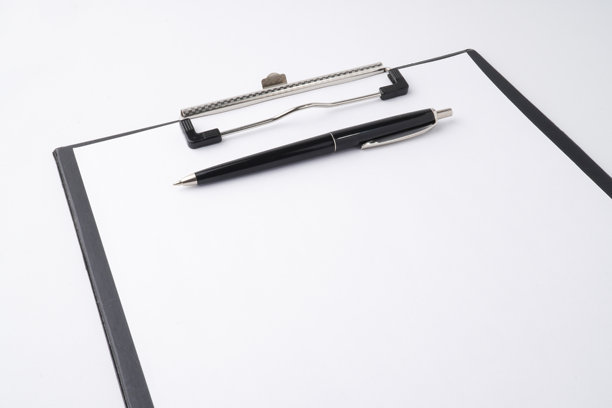 黑色文件夹和经典钢笔的特写照片，正在空白白纸上写字。背景为白色。图片下载