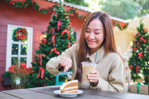 在圣诞派对上，一位女性正在享用一块胡萝卜蛋糕并喝冰咖啡的肖像照片图片下载
