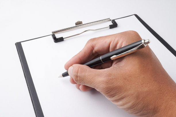一只男人的手握着一支经典的钢笔，在一张空白的白纸上写字的特写照片。背景为白色。图片下载