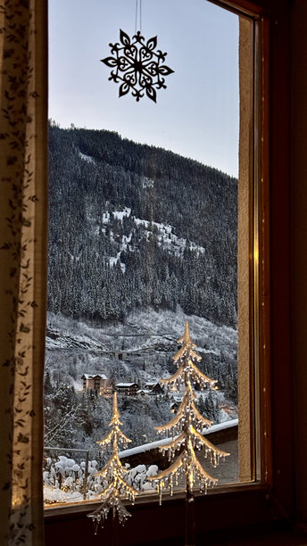温馨的家居照片，窗外是带有圣诞装饰的夜晚山景图片下载