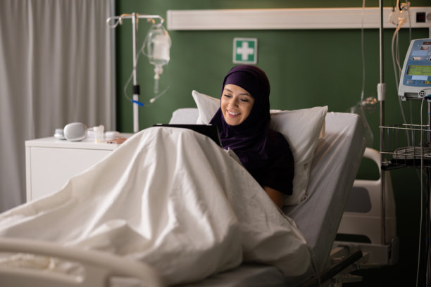 年轻的阿拉伯患者在病房里用平板电脑浏览家庭照片图片下载