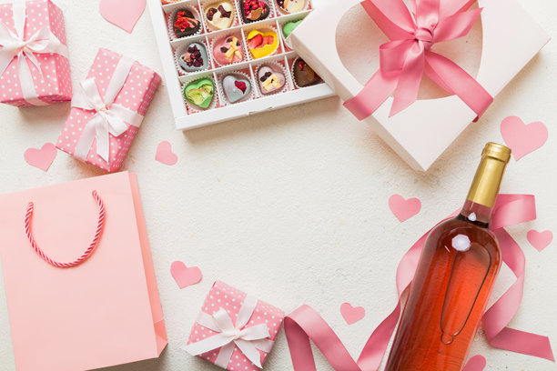 情人节装饰购物的俯视照片，包含购物袋、酒、瓶子、信封、礼物、盒子、糖果和红心，背景为彩色，留有空白空间。框架背景。图片下载