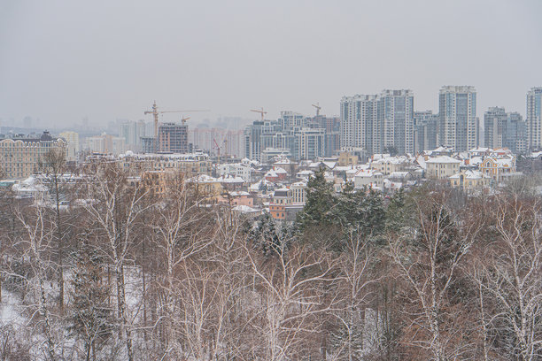 一幅彩色照片，展示了一个城市景观，雪覆盖的树木和建筑，展现了许多可能是住宅或商业的高层建筑 - 乌克兰基辅 2024年1月14日图片下载