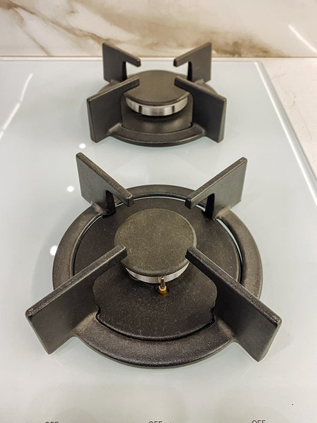 这张图片展示了两个紧密排列的燃气灶具的特写，位于洁白的炉灶台上，突显了灶具在干净背景下的精致细节。图片下载