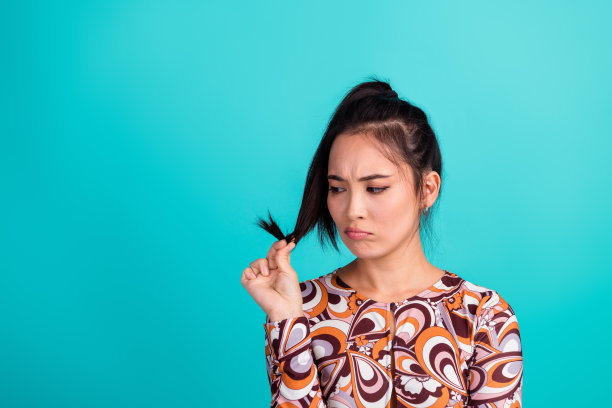 可爱的年轻女士的照片肖像，困惑的表情，受损的头发，穿着时尚的彩色衣服，背景为青色。图片下载