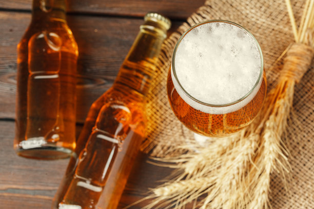 木质背景上的玻璃啤酒。创意照片。图片下载