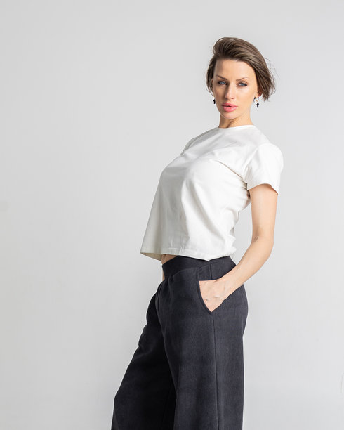 模特外貌的美丽女性肖像。女孩穿着白色T恤和黑色裤子，背景为灰色。时尚妆容的漂亮女性在摄影棚中摆姿势。竖版照片图片下载