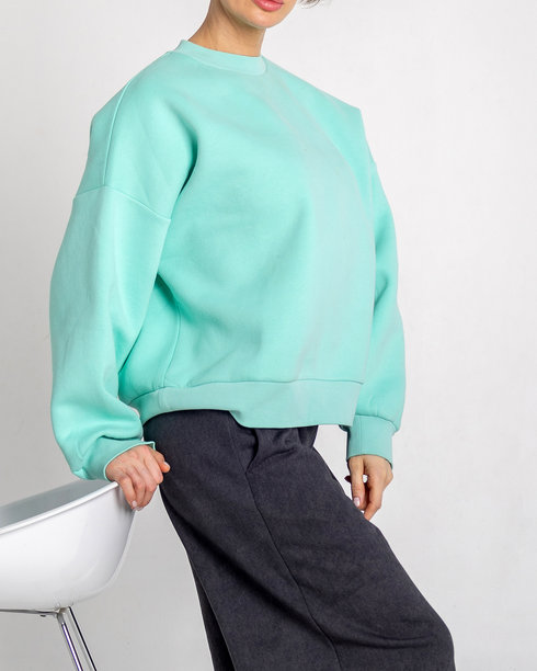 模特外貌的美丽女性肖像。女孩穿着薄荷色毛衣、黑色裤子和红色鞋子，背景为灰色。时尚妆容的漂亮女性在摄影棚中摆姿势。竖版照片图片下载