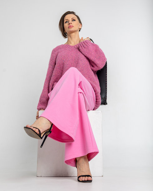 模特外貌的美丽女性肖像。女孩穿着粉色卫衣和裤子，黑色包包，背景为灰色。时尚妆容的漂亮女性在摄影棚中摆姿势。竖版照片图片下载