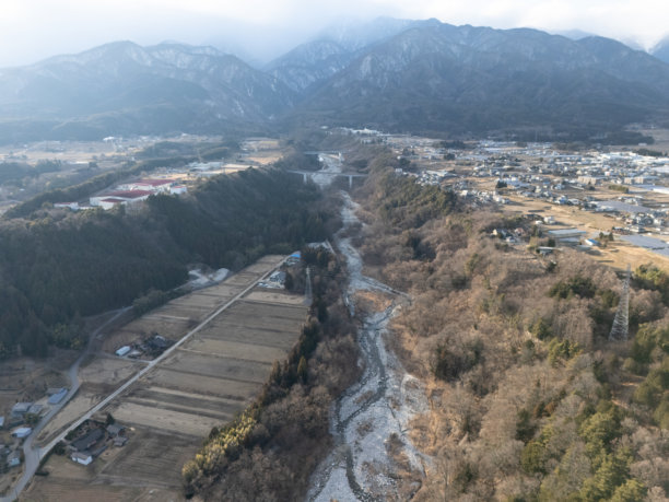 冬季日本长野县小牧市的乡村航拍照片，包括稻田和私人住宅，以及被雪覆盖的千丈岳和木曾小岐岳。图片下载