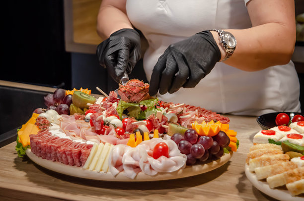一位老年女性正在准备和摆放庆祝宴会的食物，戴着黑色手套，特写镜头 - 股票照片图片下载