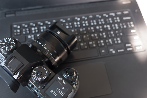 摄影师的相机镜头和笔记本电脑，用于拍摄、调整照片和清洁相机上的小灰尘的概念。图片下载