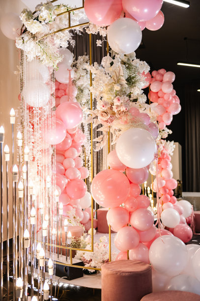 婚礼接待的照片区，或庆祝女孩生日派对的节日区域。拱门装饰着粉色和白色的气球、蜡烛和花朵。图片下载