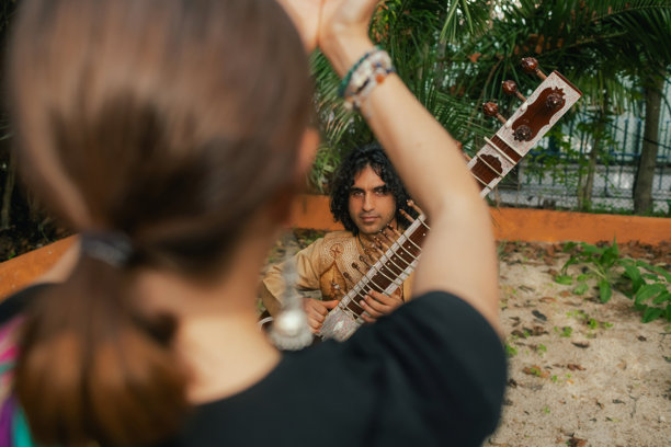 身穿传统服装的印度音乐家在户外家中演奏西塔琴，庆祝节日季节。微笑的年轻女性身着传统纱丽，跳舞享受节日。快乐的排灯节问候照片。系列的一部分。图片下载