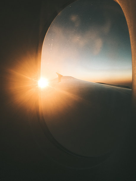 美丽的飞机机翼照片在日出时拍摄，展现出橙色、粉色和金色的鲜艳色调在地平线上扩散。图片下载